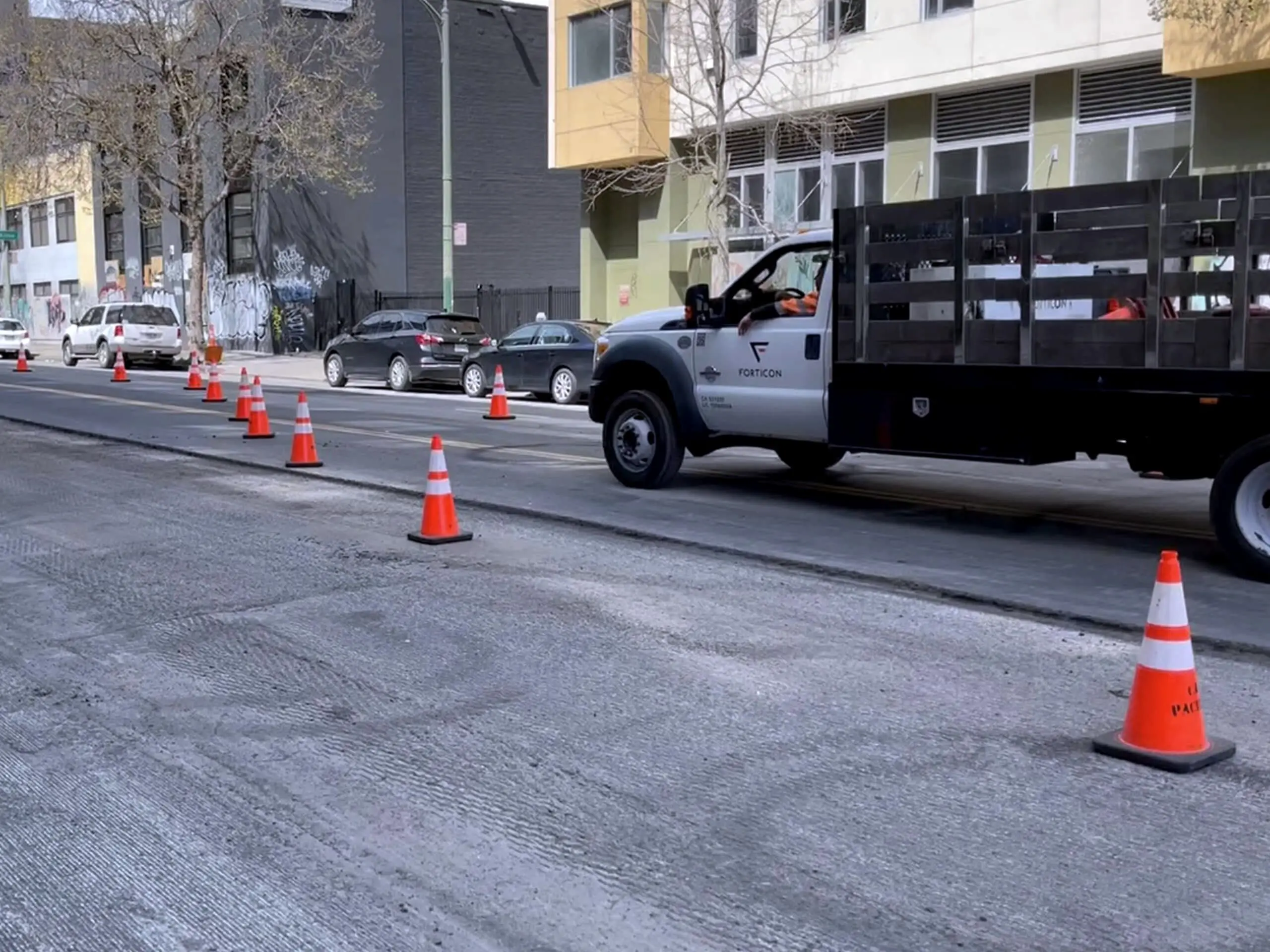 Traffic cones and a work truck holding the closure along a section of city street.