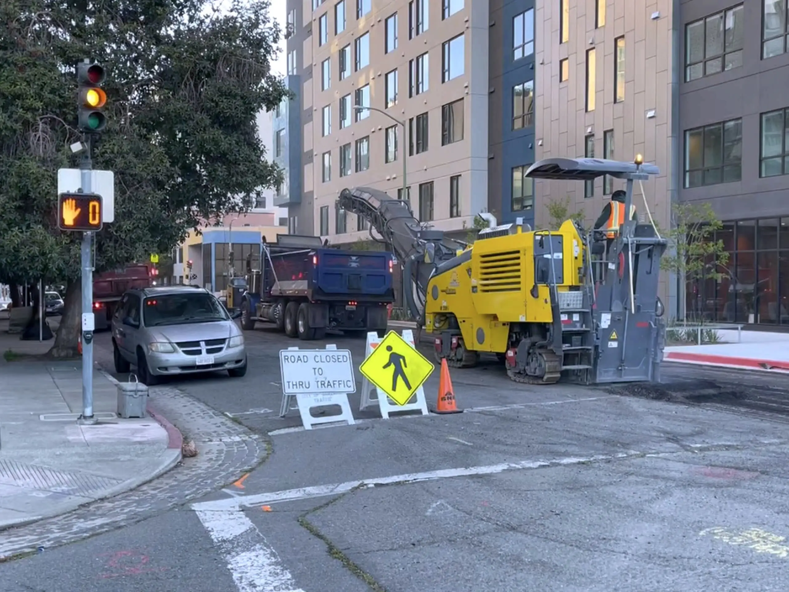 Paving plant working behind road-closed signage and barricades on 13th Street, with traffic held back.