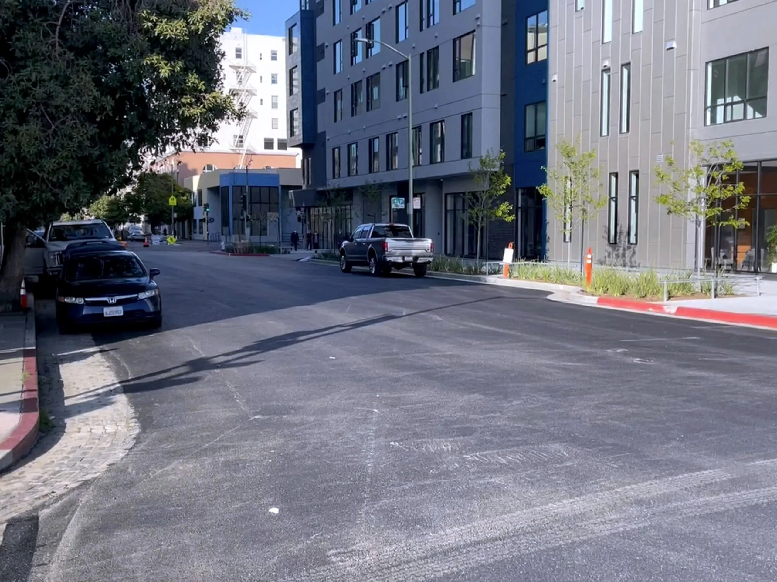 A repaved downtown Oakland street reopened to traffic alongside new apartment development.