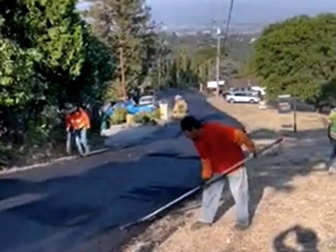 Forticon crew hand-raking the asphalt edge along a Hayward Hills street.