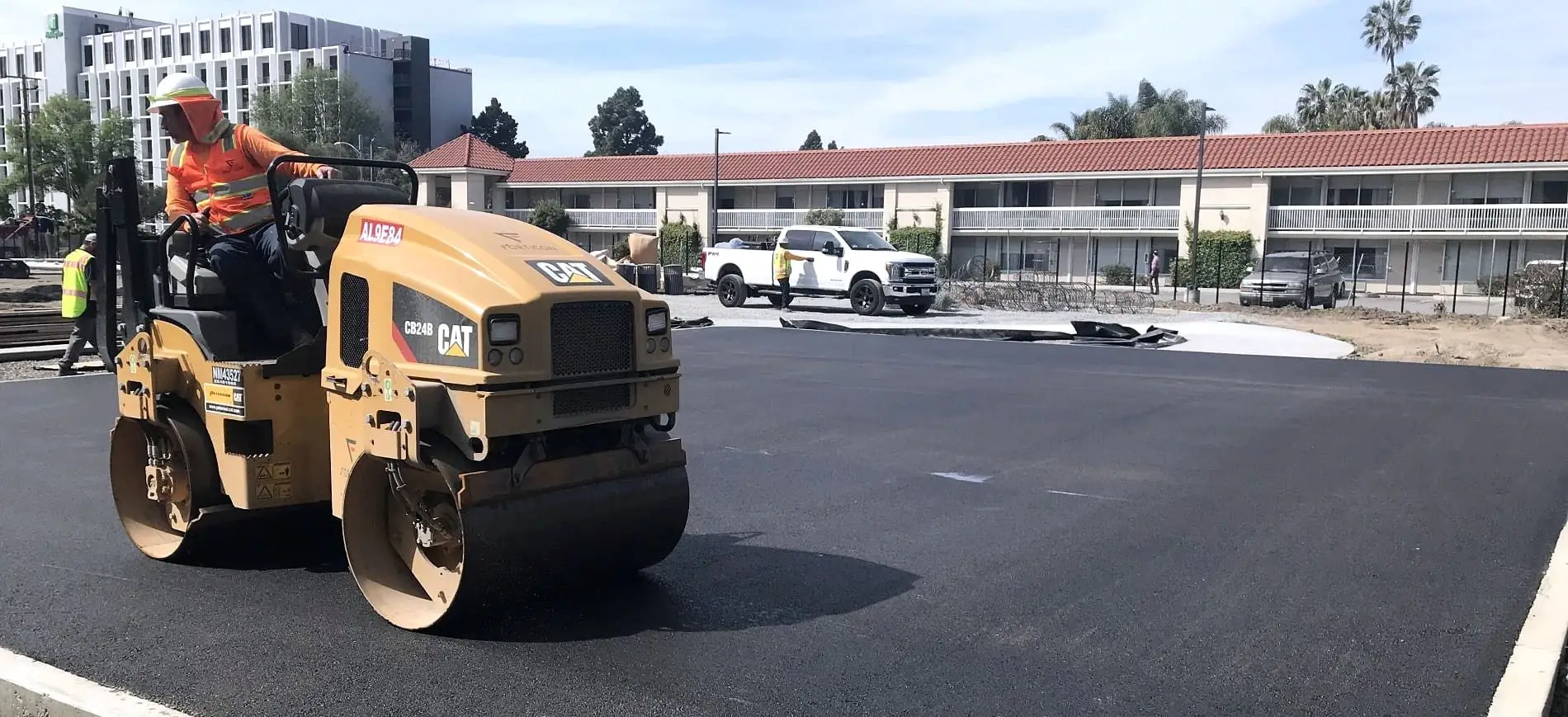 A roller compacting a newly placed asphalt mat on a Bay Area commercial site.