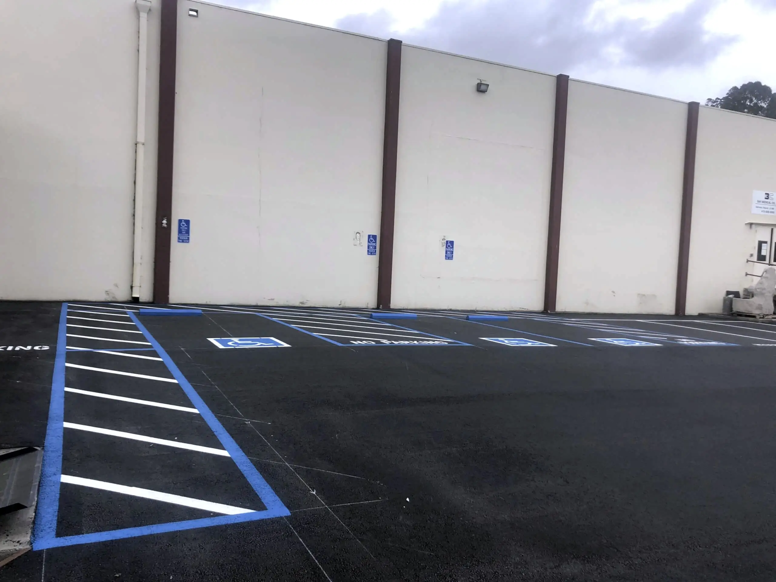 A blue-marked accessible parking stall on the newly surfaced lot at Bay Medical Co.
