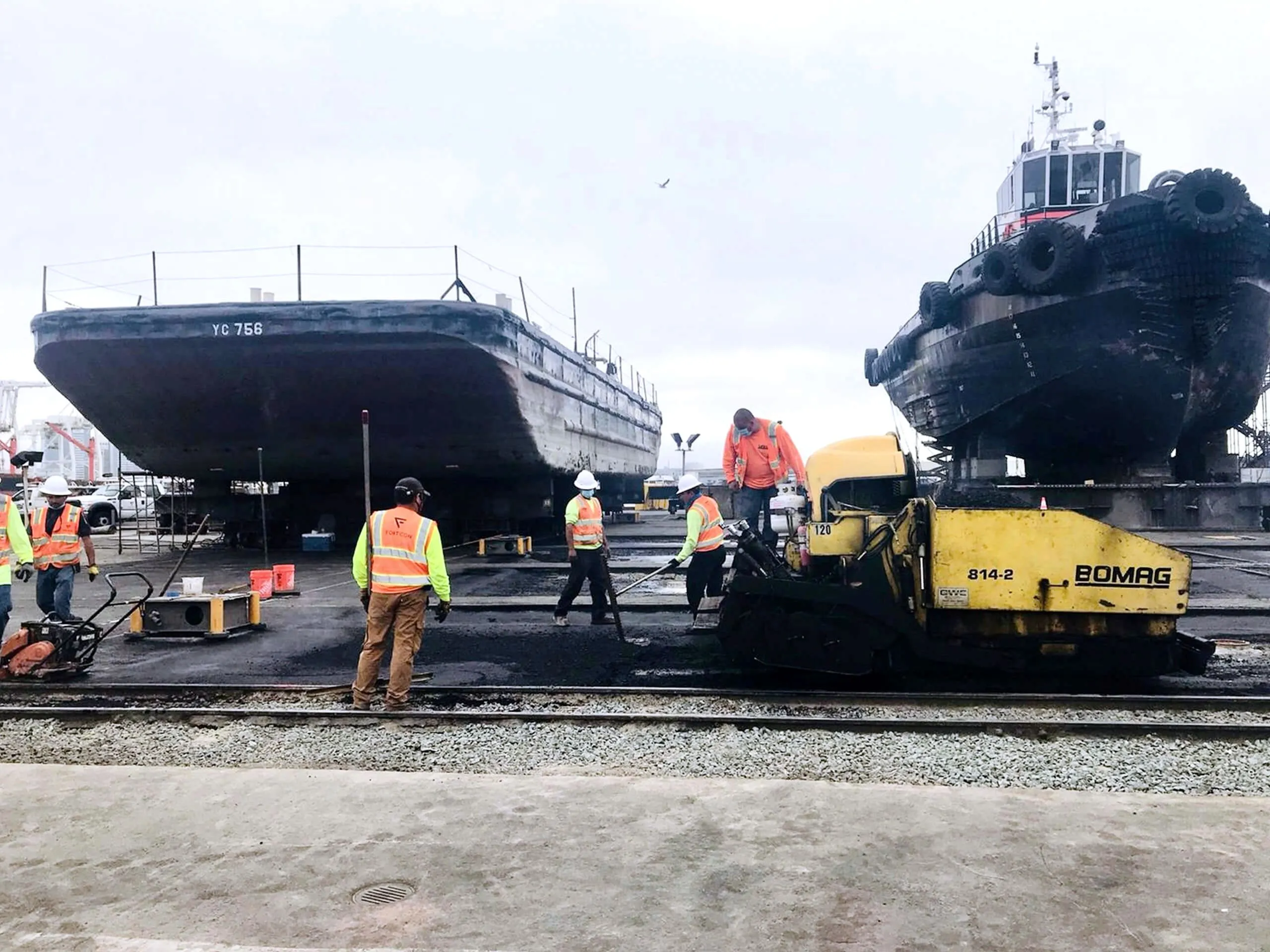 Forticon crew and paver working at the Bay Ship Co. yard in Alameda, with vessels in dry dock behind.
