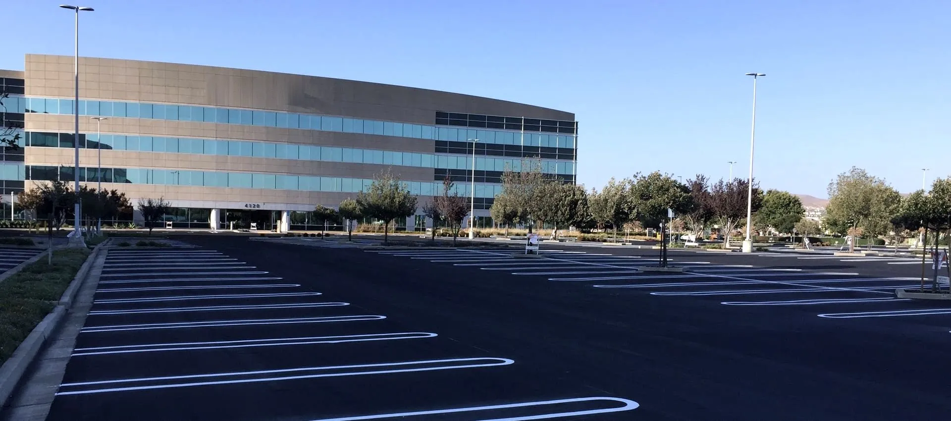 A newly paved and striped commercial parking lot in front of a multi-storey office building.