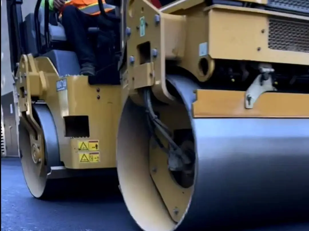 Close view of the roller drum compacting the new asphalt at the Concord dealership.