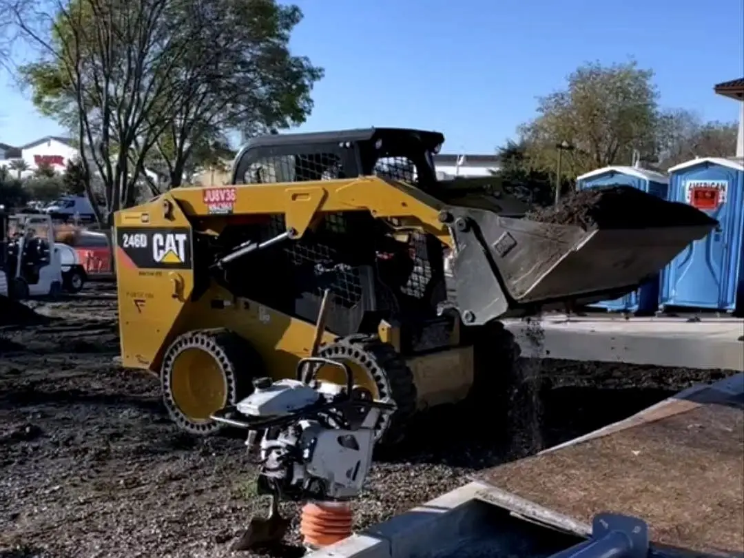 A skid steer working the exposed subgrade before the new section is built at Diamond Blvd.