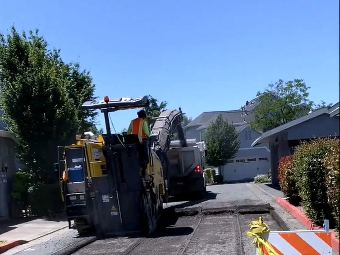 A milling machine and operator removing the existing surface on a Marin Lagoon roadway.