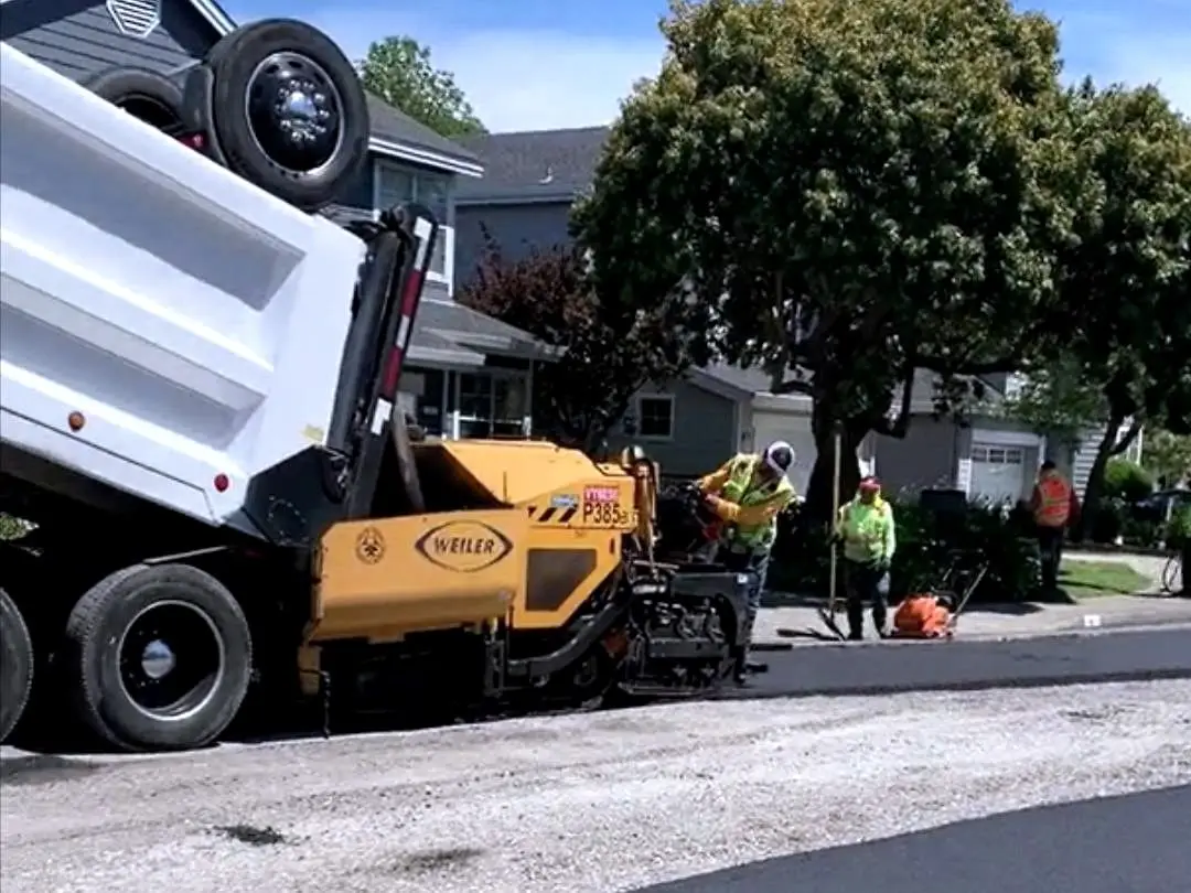 A dump truck feeding the paver on Bridgewater Drive, San Rafael.