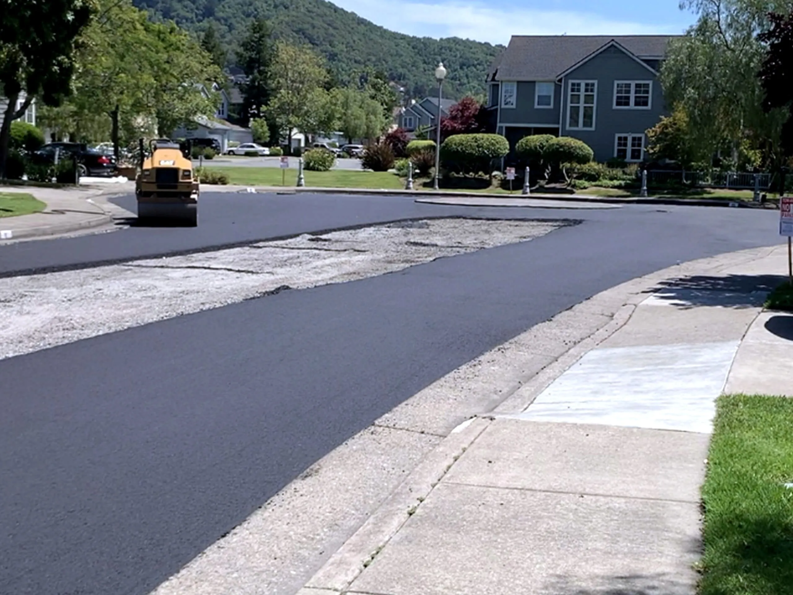 A completed roadway at Marin Lagoon in San Rafael curving past homes, with the Marin hills behind.