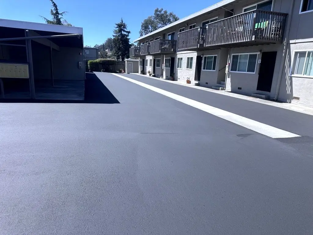 Looking along the finished sealed alley beside the apartment building, with the concrete gutter crossing it diagonally.